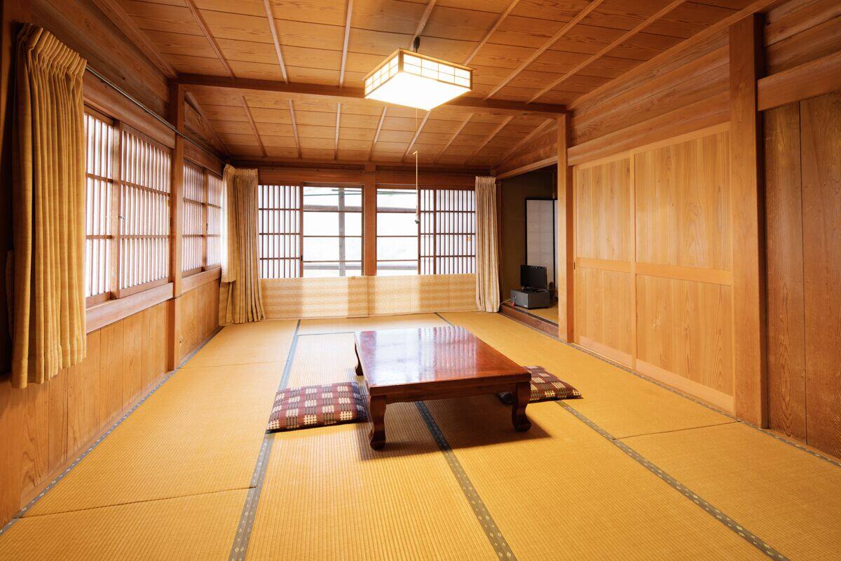 A traditional Japanese room with tatami flooring, a low wooden table, sliding doors, and a ceiling light fixture.