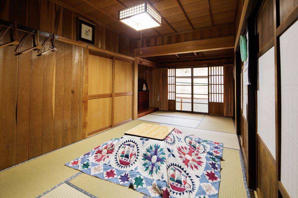 A traditional Japanese room with tatami flooring, wooden walls, a shoji screen, and a hanging shoji.