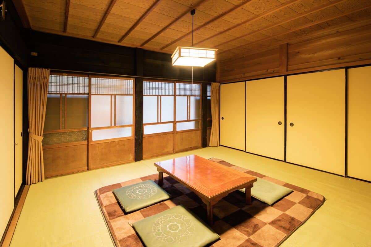 Una habitación tradicional japonesa con suelo de tatami, una mesa de madera baja y puertas correderas.