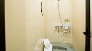 Een kleine, goed verlichte badkamer met een douche, toilet en handdroger.