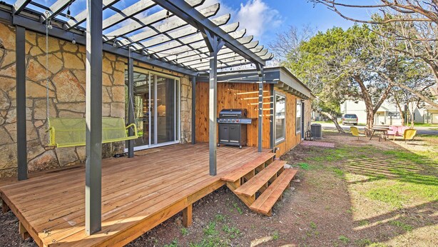 A covered outdoor area with a wooden deck, a grill, and a pergola structure.