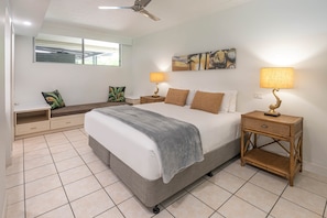 A bedroom with a bed, two bedside tables with lamps, a bench, and a wall-mounted artwork.