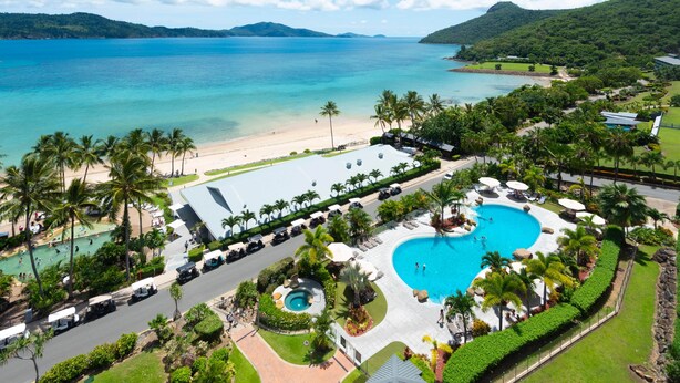 A resort with a large pool, beach access, and lush greenery.