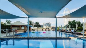 An indoor swimming pool with clear water, surrounded by lounge areas and palm trees.