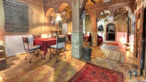 A cozy interior with a tiled floor, a dining area with a table and chairs, and a decorative wall with a clock. - inn the Fibula of Dades (Boumalne Dadès)