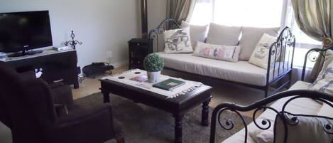 A living room with a sofa, a coffee table, a TV, and a small plant.