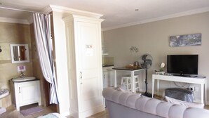 Une chambre d’hôtel comprenant un lit, un canapé, un bureau avec une télévision, une kitchenette et une salle de bain.