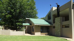Une maison moderne à deux étages, dotée d’un toit végétalisé, d’une façade en pierre et d’une pelouse bien entretenue.