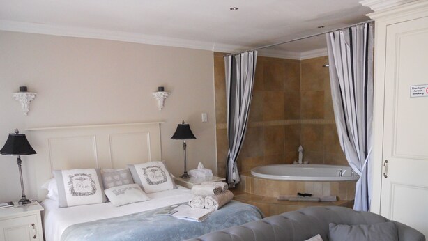 Une chambre d’hôtel comprenant un lit, un canapé, une salle de bain avec baignoire et un panneau indiquant qu’il est interdit de fumer.
