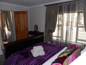 Ein Schlafzimmer mit einem Bett, einer violett gestreiften Bettdecke und einem Holzkopfstück.