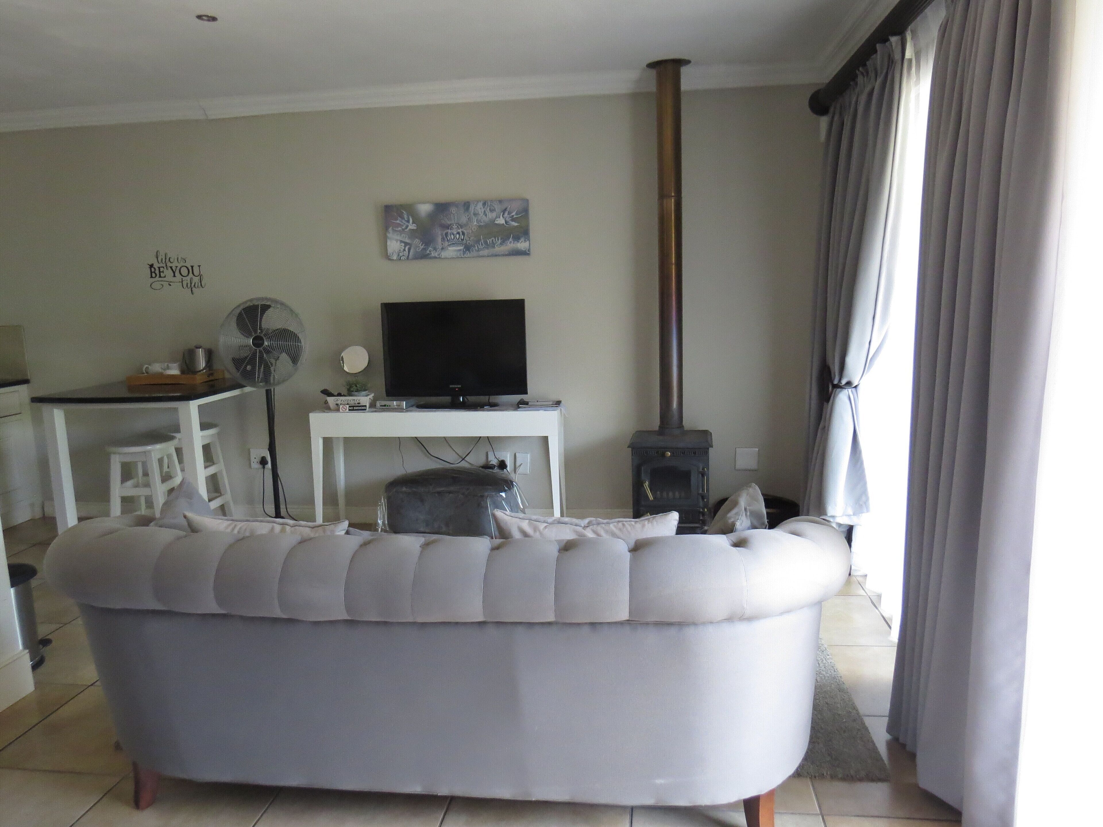 A living room with a sofa, a television, a fireplace, and a dining area with a table and chairs.