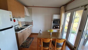 A modern kitchen with wooden cabinets, a white refrigerator, and a dining area with two wooden chairs. - German Village Gelbe Haus (Namhae)