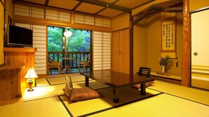 A traditional Japanese room with tatami flooring, a low table, cushions, a television, and a sliding door leading to a balcony. - Kurokawa Onsen Okunoyu (Minamioguni)