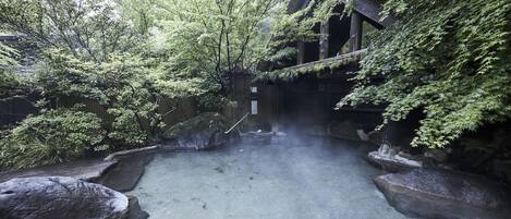 Un jardí japonès tradicional amb un camí de pedra, roques grans i vegetació exuberància.