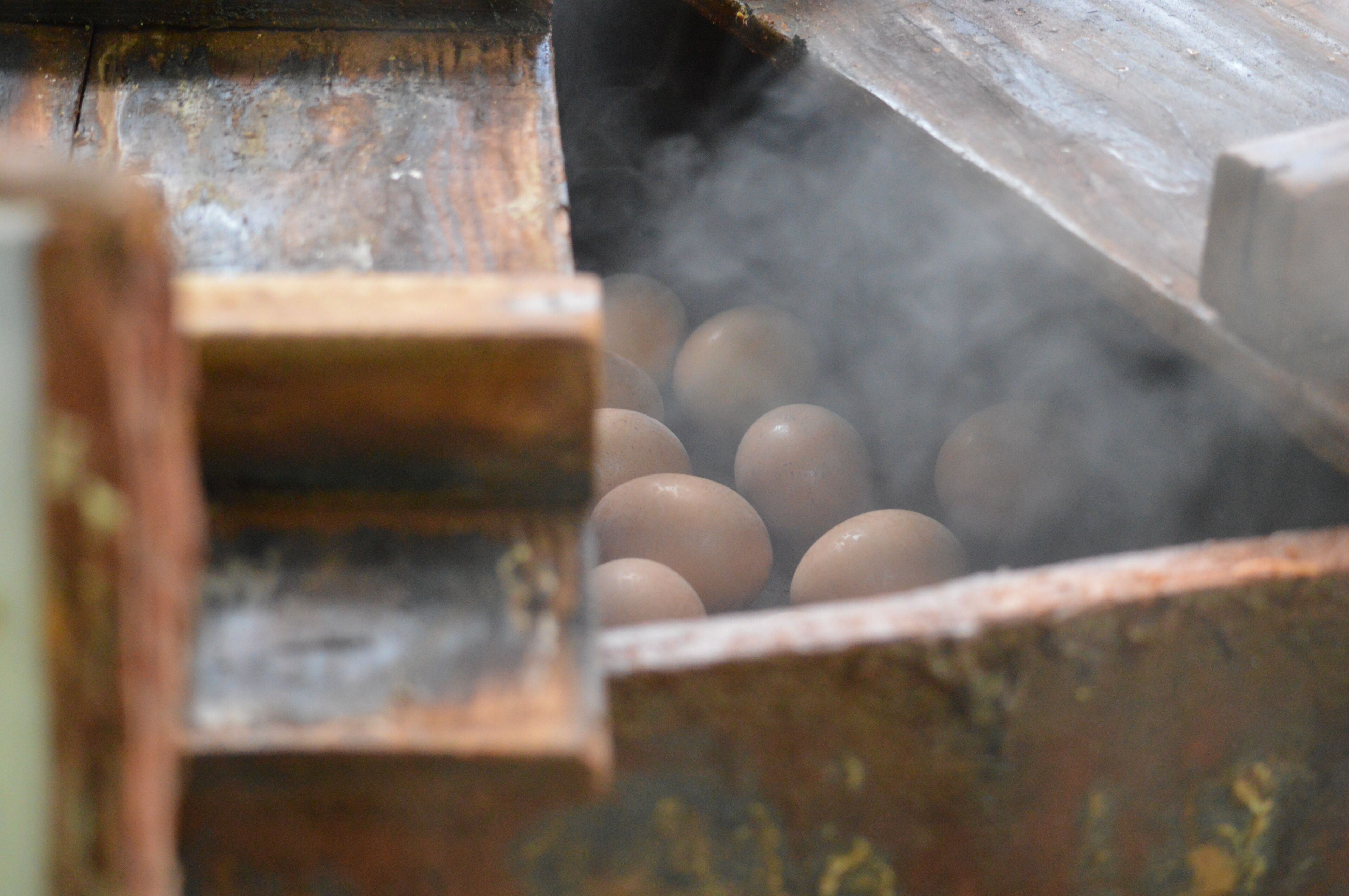 A close-up of eggs in a wooden container with steam rising from them.