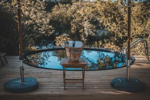 A wooden deck with a table and a wicker basket, overlooking a swimming pool and surrounded by trees. - Klaserie Sands Safari Trails (Bushbuckridge)