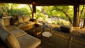 Een gezellig buiten zitgedeelte met een bank, een ronde tafel en een comfortabele zitting, met uitzicht op een natuurlandschap.