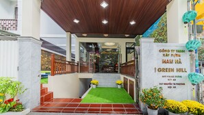 A hotel entrance with a wooden ceiling, a green artificial lawn, and potted plants. - Green Hill Hotel (Da Nang)