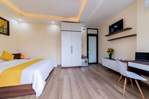 Une chambre d’hôtel comprenant un lit, un bureau, une chaise, une télévision et une armoire.