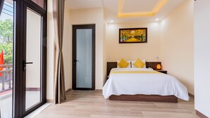 A bedroom with a large bed, a glass door, and a painting on the wall. - Green Hill Hotel (Da Nang)