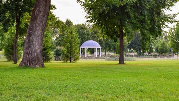 A gazebo in a park with a grassy field and trees.