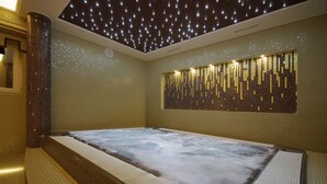 A hot tub with a tiled wall and a ceiling with star-like lights. - Arcanum Hotel (Bekescsaba)