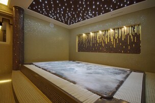 Un jacuzzi con pared de azulejos e iluminación en el techo que simula estrellas.