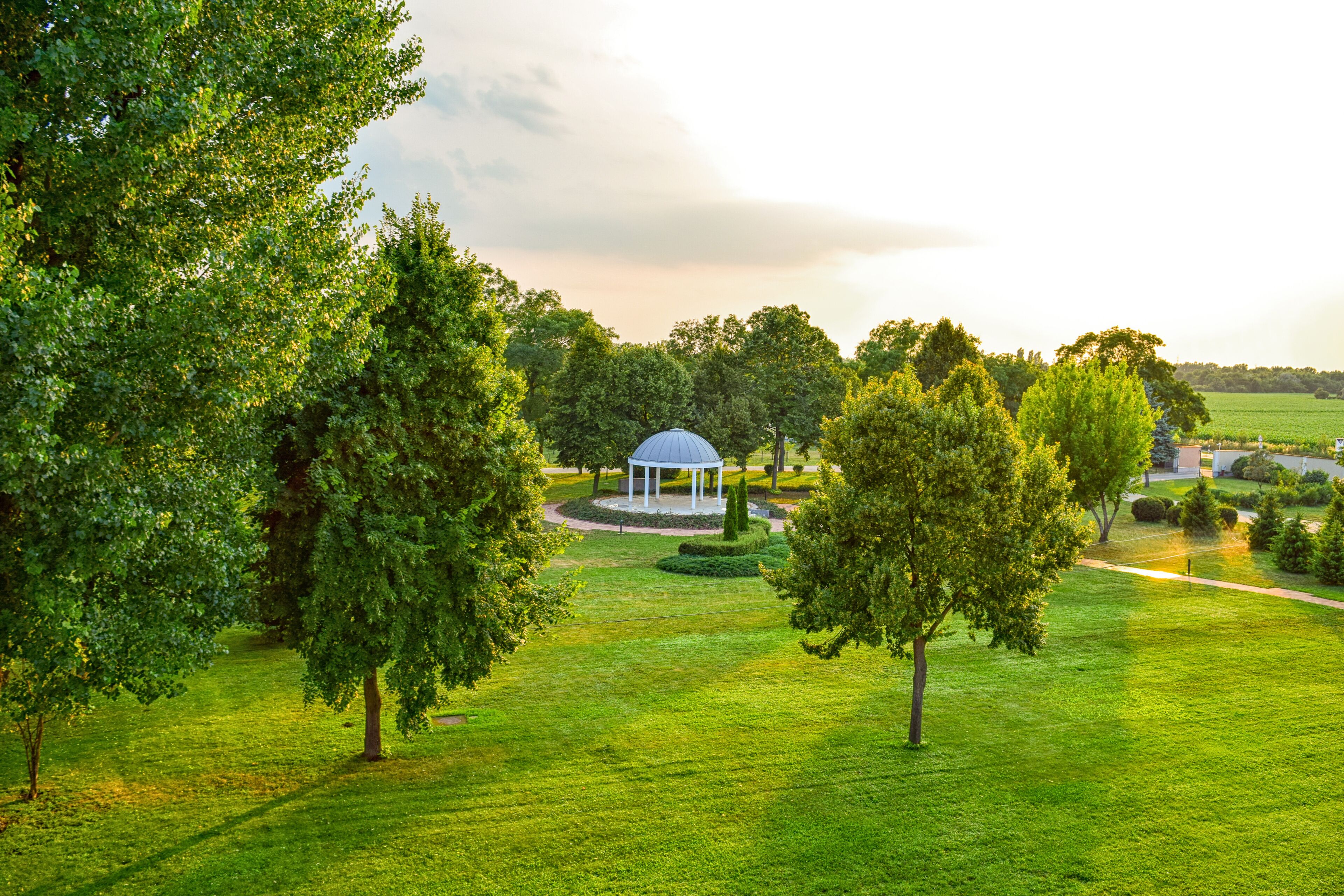 A gazebo in a park with lush green grass and trees.
