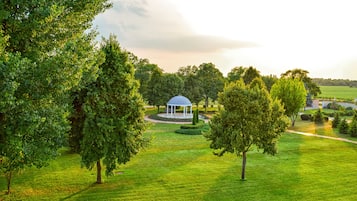 A gazebo in a park with lush green grass and trees.