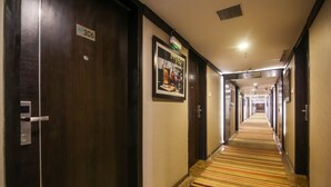 En hotellkorridor med ett randigt golv, trädörrar och en inramad tavla på väggen.