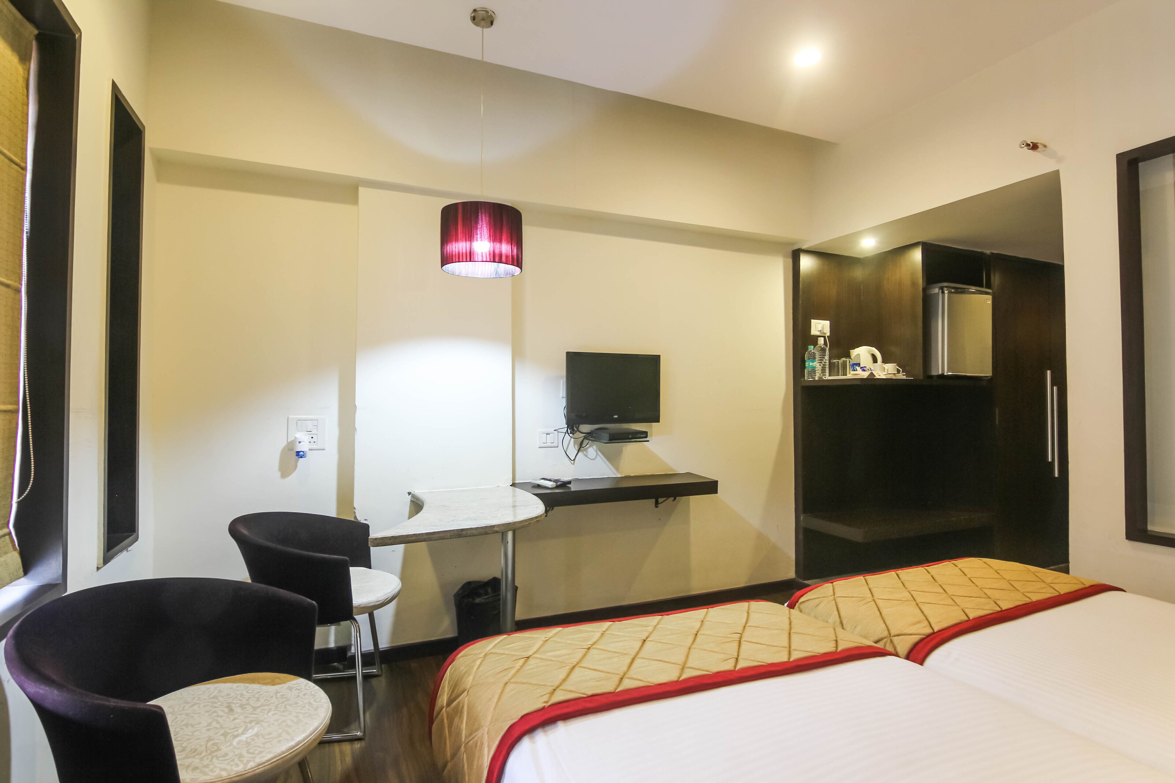 A hotel room with a bed, a desk, a chair, a TV, and a wardrobe.
