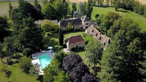 Un vaste domaine comprenant plusieurs bâtiments, une piscine et une pelouse bien entretenue.