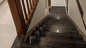 A staircase with wooden handrails and black marble steps leading to a landing. - Hotel Flora Suites (Mumbai)