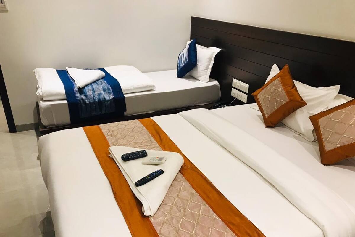 A hotel room with two beds, each with white linens and decorative pillows.