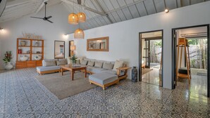 A spacious living area with a high ceiling, a sofa set, a coffee table, and a dining table. There are ceiling fans, pendant lights, and a view of the outside through an open door. - 10-bedroom private estate in Seminyak, perfect for large groups, family gatherings, retreats, and celebrations. Enjoy daily breakfast, a private chef, airport transfers, complimentary massages, housekeeping, and a dedicated driver. (Seminyak)