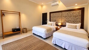 A hotel room with two beds, a wooden wardrobe, a hanging chair, and a textured rug.
