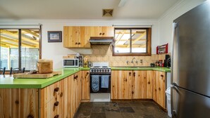 A kitchen with wooden cabinets, a green countertop, a stove, a microwave, and a refrigerator. - Flinders Ranges Bed and Breakfast (HAWKER)