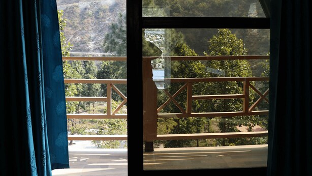 A room with a large window overlooking a mountainous landscape. - Rakatal Rocks Resort (Lansdowne)