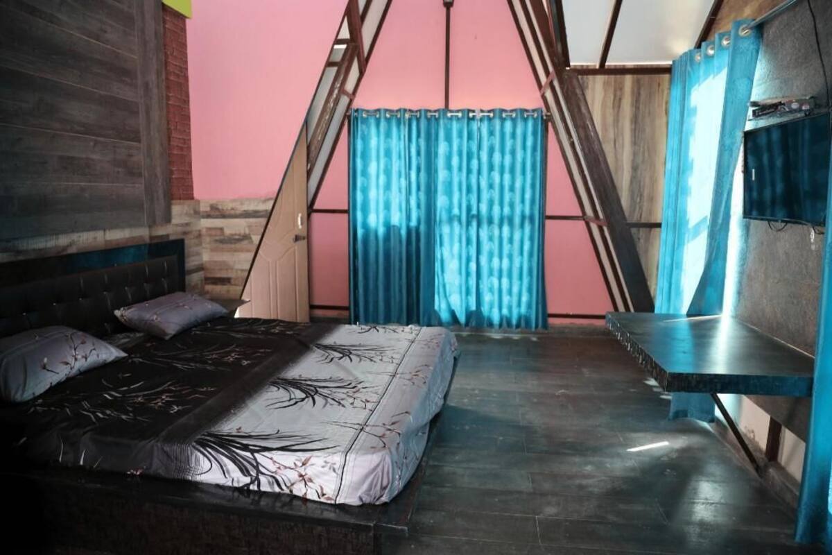 Una habitación con cama, un banco y una ventana con cortinas.