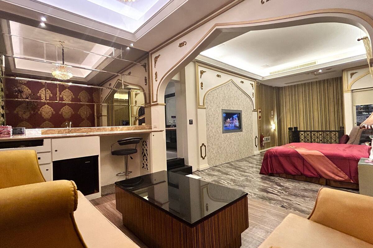 A hotel room with a dining area, a TV, a bed, and a sofa.