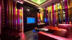 A modern living room with a TV, red leather sofa, and a small table. - Shining Motel (Taichung)