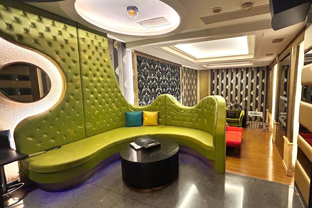 A modern lounge area with a green upholstered sofa, a round coffee table, and a patterned wall.
