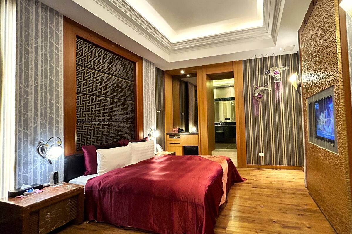 A hotel room with a large bed, a vanity, a television, and a bathroom visible through an open door.