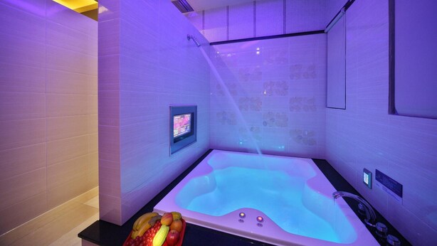 A modern spa room with a hot tub, a digital control panel, and a fruit bowl on the counter. - Shining Motel (Taichung)