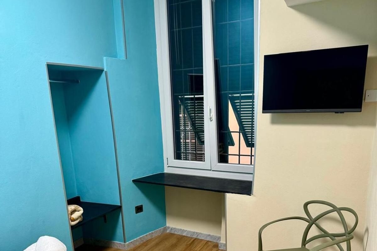 A room with a bed, a chair, a window, and a TV.