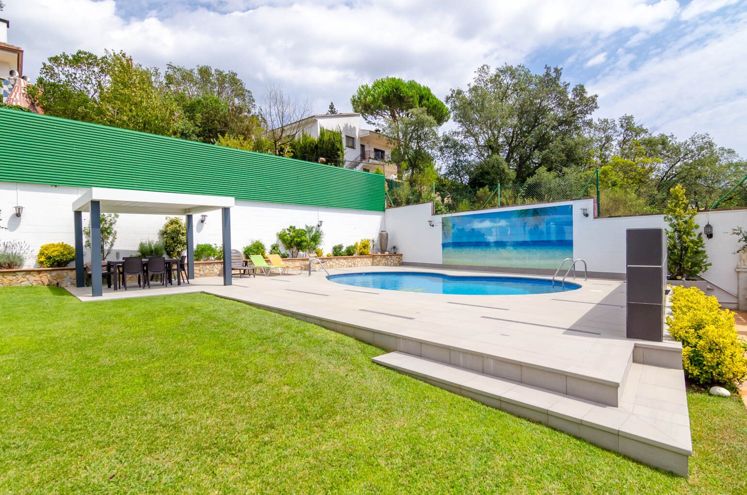 A backyard with a swimming pool, a covered patio, and a grassy lawn.