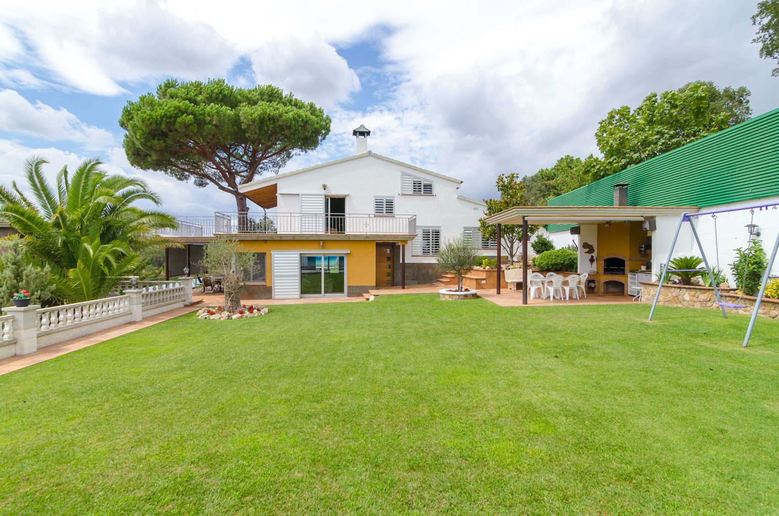 A two-story house with a covered patio and a swing set.