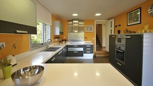Una cocina moderna con una isla central, electrodomésticos integrados y vistas al comedor.