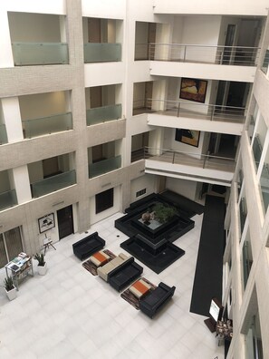 A multi-level atrium with a central courtyard, glass railings, and a variety of seating arrangements.