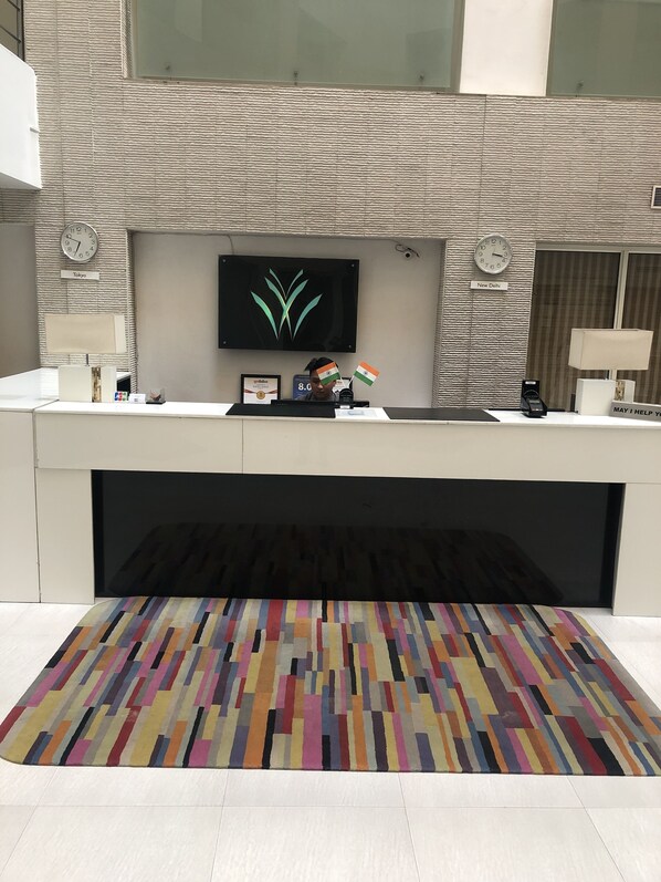 A reception desk with clocks, a framed certificate, and a colorful rug.
